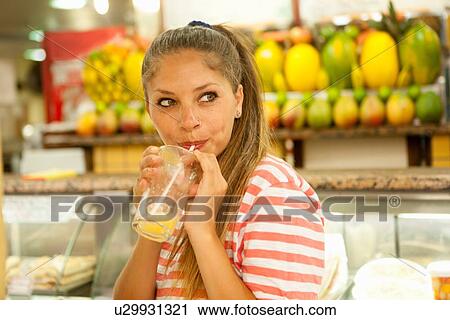 Stock Image - "Young female tourist drinking in juice bar, Copacabana town, Rio De Janeiro, Brazil". Fotosearch