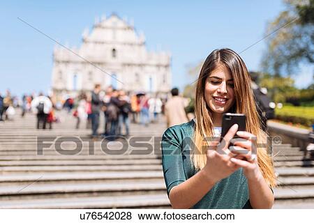 "Young female tourist reading smartphone texts in front of St Pauls Cathedral ruins, Macau, Hong Kong, China" View Large Photo Image Stock Photo - "Young female tourist reading smartphone texts in front of St Pauls Cathedral ruins, Macau, Hong Kong, China". Fotosearch