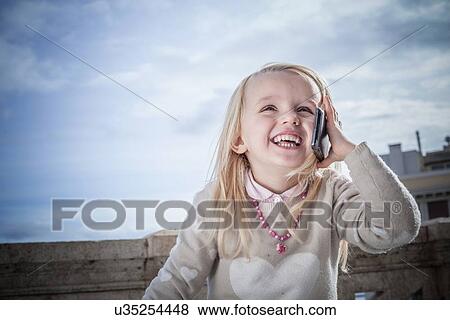 Stock Photo - "Young girl laughing and chatting on smartphone, Cagliari, Sardinia, Italy". Fotosearch