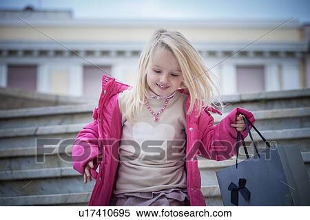 Stock Photography - "Young girl on stairway carrying shopping bag, Cagliari, Sardinia, Italy". Fotosearch