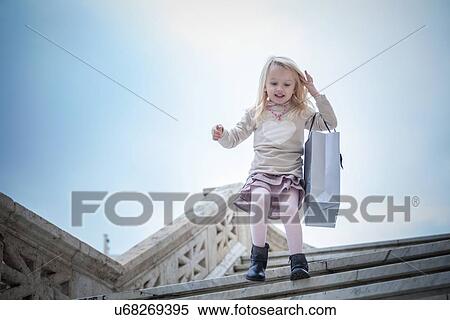 Stock Photography - "Young girl running down stairway carrying shopping bag, Cagliari, Sardinia, Italy". Fotosearch