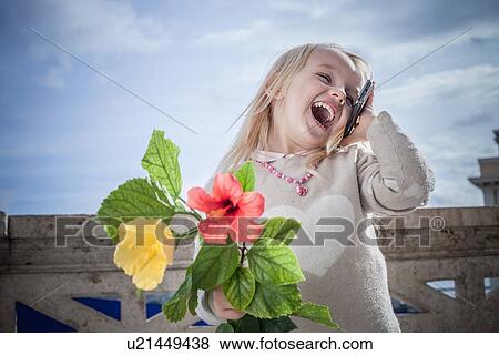 "Young girl with flowers laughing and chatting on smartphone, Cagliari, Sardinia, Italy" View Large Photo Image Stock Photo - "Young girl with flowers laughing and chatting on smartphone, Cagliari, Sardinia, Italy". Fotosearch