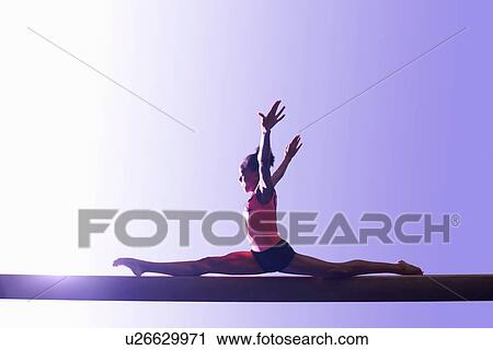 Stock Image - Young gymnast performing on balance beam. Fotosearch