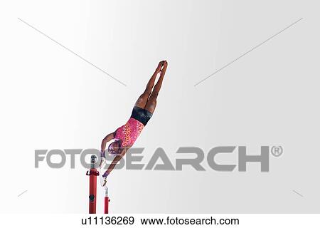 Stock Photo - Young gymnast performing on uneven bars. Fotosearch