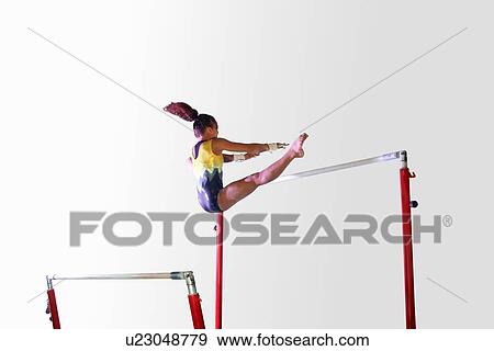 Stock Photo - Young gymnast performing on uneven bars. Fotosearch