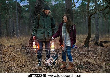 Young hiking couple with lanterns walking dog in woods View Large Photo Image Stock Photo - Young hiking couple with lanterns walking dog in woods. Fotosearch