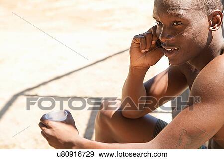 Young male basketball player drinking water and chatting on smartphone View Large Photo Image Stock Photo - Young male basketball player drinking water and chatting on smartphone. Fotosearch