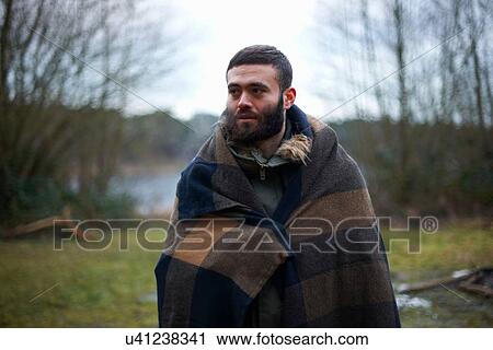 Young male camper wrapped in blanket in woods View Large Photo Image Stock Image - Young male camper wrapped in blanket in woods. Fotosearch