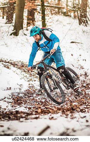 Young male mountain biker speeding on snow covered forest track View Large Photo Image Stock Photo - Young male mountain biker speeding on snow covered forest track. Fotosearch