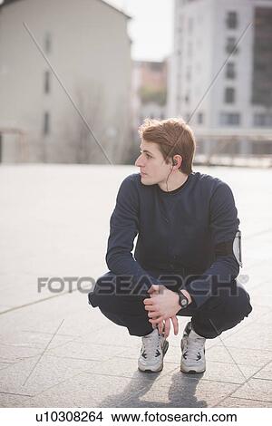 Picture - Young male runner crouching in city square. Fotosearch