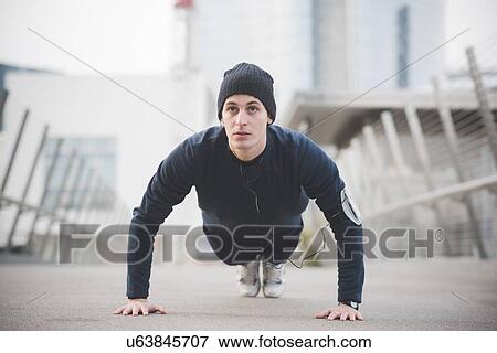 Young male runner doing press ups on city footbridge View Large Photo Image Stock Photo - Young male runner doing press ups on city footbridge. Fotosearch