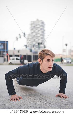 Young male runner doing push ups in city square View Large Photo Image Stock Photo - Young male runner doing push ups in city square. Fotosearch