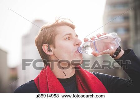 Stock Photo - Young male runner drinking water. Fotosearch
