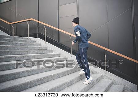 Stock Image - Young male runner moving up city stairs. Fotosearch
