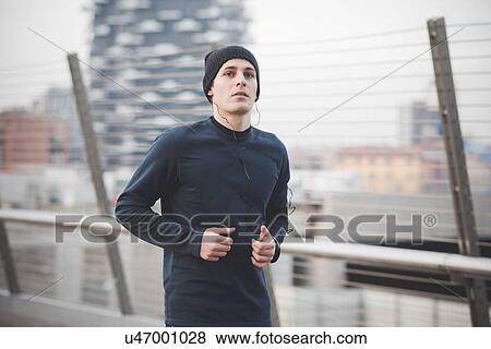 Stock Photo - Young male runner running on city footbridge. Fotosearch