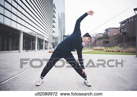 Young male runner stretching in city View Large Photo Image Stock Image - Young male runner stretching in city. Fotosearch