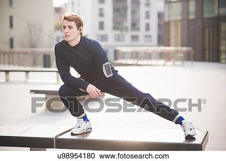 Young male runner stretching in city square View Large Photo Image Stock Image - Young male runner stretching in city square. Fotosearch