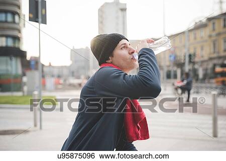Young male runner taking a drink break in city View Large Photo Image Stock Photograph - Young male runner taking a drink break in city. Fotosearch