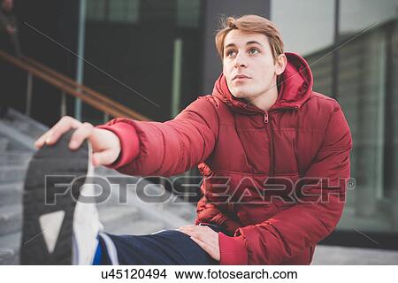 Picture - Young male runner touching toes on city stairway. Fotosearch