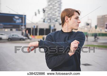 Stock Photograph - Young male runner warming up in city square. Fotosearch