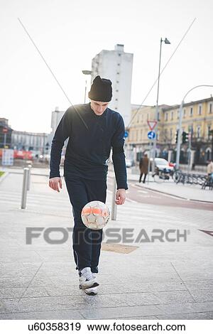 Young male soccer player playing keepy uppy on city street View Large Photo Image Stock Photo - Young male soccer player playing keepy uppy on city street. Fotosearch