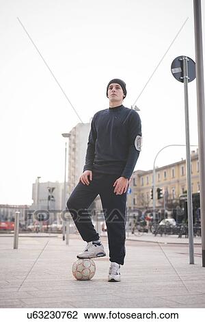 Young male soccer player with foot on soccer ball on city street View Large Photo Image Stock Image - Young male soccer player with foot on soccer ball on city street. Fotosearch