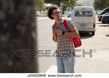 Stock Photo - "Young male tourist looking over his shoulder, Copacabana, Rio De Janeiro, Brazil". Fotosearch