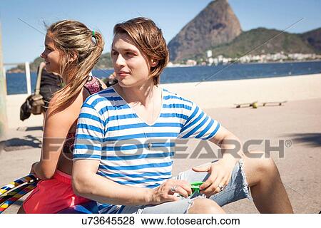 "Young man and woman sitting back to back, outdoors" View Large Photo Image Stock Photo - "Young man and woman sitting back to back, outdoors". Fotosearch