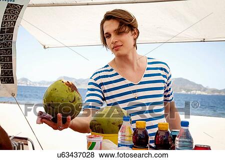 Young man buying coconut from kiosk View Large Photo Image Stock Photo - Young man buying coconut from kiosk. Fotosearch