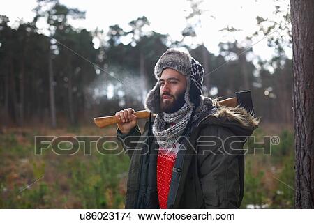 Young man carrying axe over his shoulder in forest View Large Photo Image Picture - Young man carrying axe over his shoulder in forest. Fotosearch