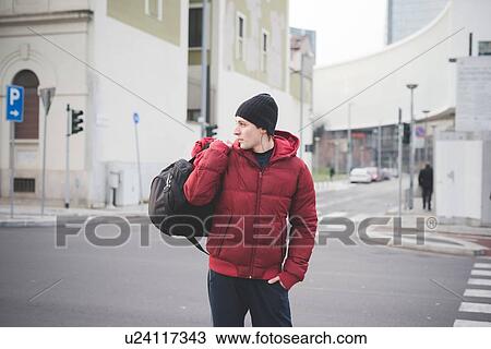 Stock Image - Young man carrying holdall on city street. Fotosearch