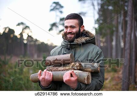Young man collecting logs for campfire in forest View Large Photo Image Stock Photograph - Young man collecting logs for campfire in forest. Fotosearch