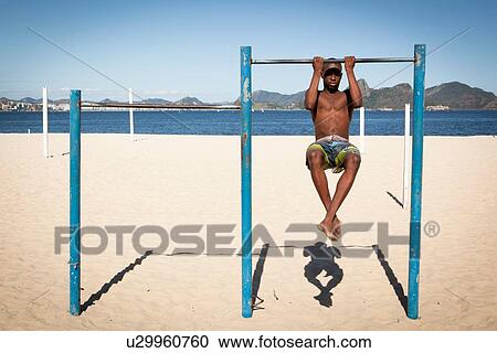 Young man doing chin ups on beach View Large Photo Image Stock Image - Young man doing chin ups on beach. Fotosearch