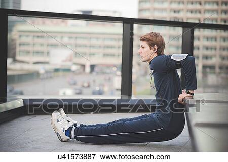 Stock Photo - Young man doing reverse push ups on city rooftop. Fotosearch