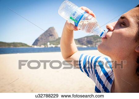 Stock Photo - "Young man drinking from water bottle, outdoors, close-up". Fotosearch