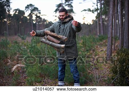 Young man dropping logs for campfire in forest View Large Photo Image Stock Photo - Young man dropping logs for campfire in forest. Fotosearch