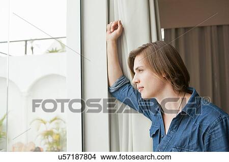 Picture - Young man gazing out of hotel doorway. Fotosearch
