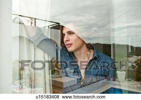 Young man gazing out of hotel window View Large Photo Image Stock Photo - Young man gazing out of hotel window. Fotosearch