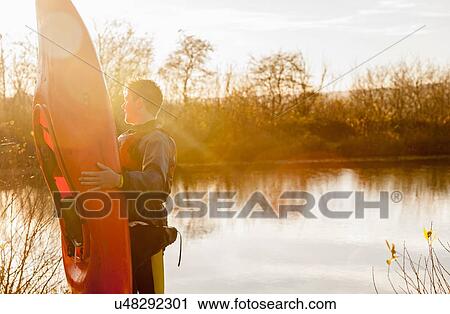 Young man holding kayak by lake View Large Photo Image Stock Image - Young man holding kayak by lake. Fotosearch