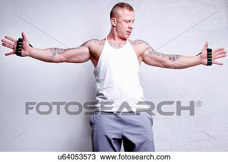 "Young man holding resistance bands, arms outstretched" View Large Photo Image Stock Image - "Young man holding resistance bands, arms outstretched". Fotosearch