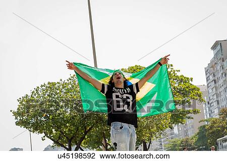 "Young man holding up Brazilian flag, Copacabana, Rio De Janeiro, Brazil" View Large Photo Image Stock Image - "Young man holding up Brazilian flag, Copacabana, Rio De Janeiro, Brazil". Fotosearch