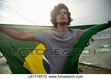 "Young man holding up Brazilian flag, Ipanema beach, Rio De Janeiro, Brazil" View Large Photo Image Stock Image - "Young man holding up Brazilian flag, Ipanema beach, Rio De Janeiro, Brazil". Fotosearch
