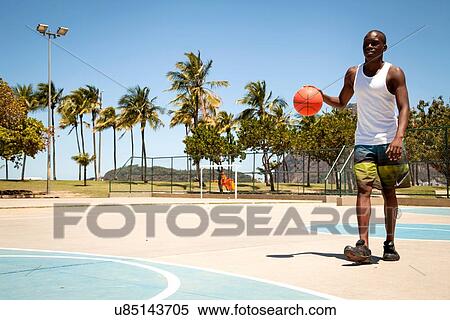 Stock Photography - Young man practicing basketball on basketball court. Fotosearch