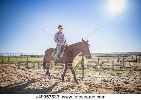 Stock Image - Young man riding horse. Fotosearch