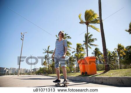 "Young man skateboarding along road, low angle view" View Large Photo Image Stock Image - "Young man skateboarding along road, low angle view". Fotosearch