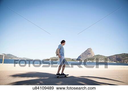 Stock Photo - Young man skateboarding on pavement. Fotosearch