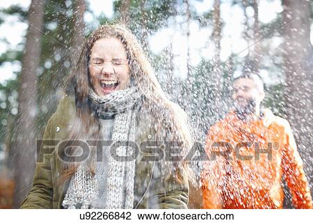 Stock Image - Young man sprinkling girlfriend with water in forest. Fotosearch