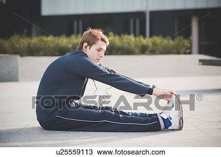 Young man touching toes in city square View Large Photo Image Stock Image - Young man touching toes in city square. Fotosearch