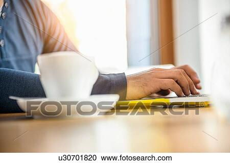 "Young man using laptop in cafe, mid section" View Large Photo Image Stock Image - "Young man using laptop in cafe, mid section". Fotosearch