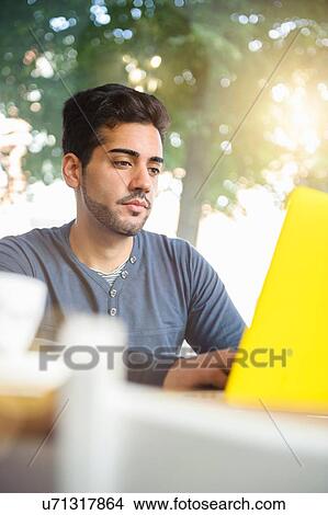 Picture - Young man using laptop in cafe. Fotosearch